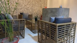A room with wicker furniture, a stone wall, and a modern light fixture.