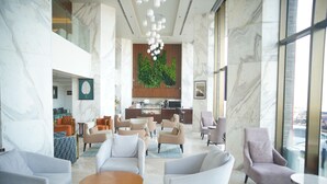 A spacious lobby with marble walls, multiple seating areas, a kitchen in the background, and large windows offering a view. - Ramada by Wyndham Cox's Bazar Kolatoli Beach (Cox's Bazar)