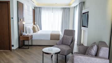 Una habitación de hotel moderna con una cama bien hecha, un sofá, una mesita y un televisor montado en la pared.