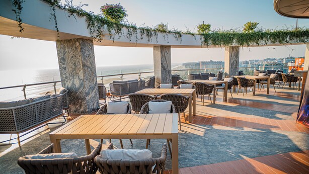 An outdoor terrace with wooden flooring, wicker furniture, and a view of the sea. - Ramada by Wyndham Cox's Bazar Kolatoli Beach (Cox's Bazar)
