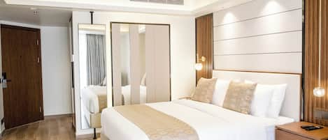 A modern hotel room with a large bed, a wooden nightstand, and a mirror.