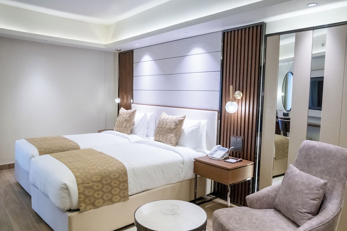 Une chambre d’hôtel avec un grand lit, une table de chevet avec un téléphone, une chaise et une table ronde.
