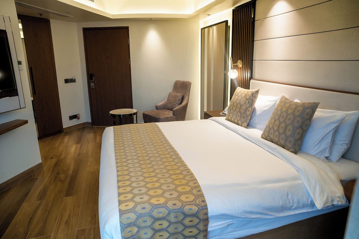 Une chambre d’hôtel avec un grand lit, une chaise, une petite table et un téléviseur fixé au mur.
