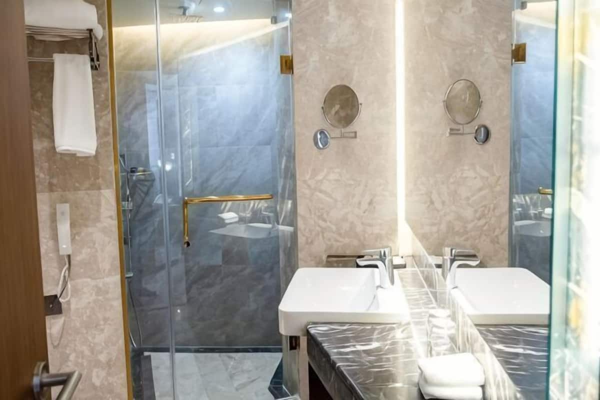 Une salle de bain moderne dotée d’une douche à parois de verre, de deux vasques et d’un plan de toilette en marbre.