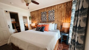 Ein Schlafzimmer mit einem großen Bett, Holzwandverkleidungen, zwei Wandlampen und einem Deckenventilator.