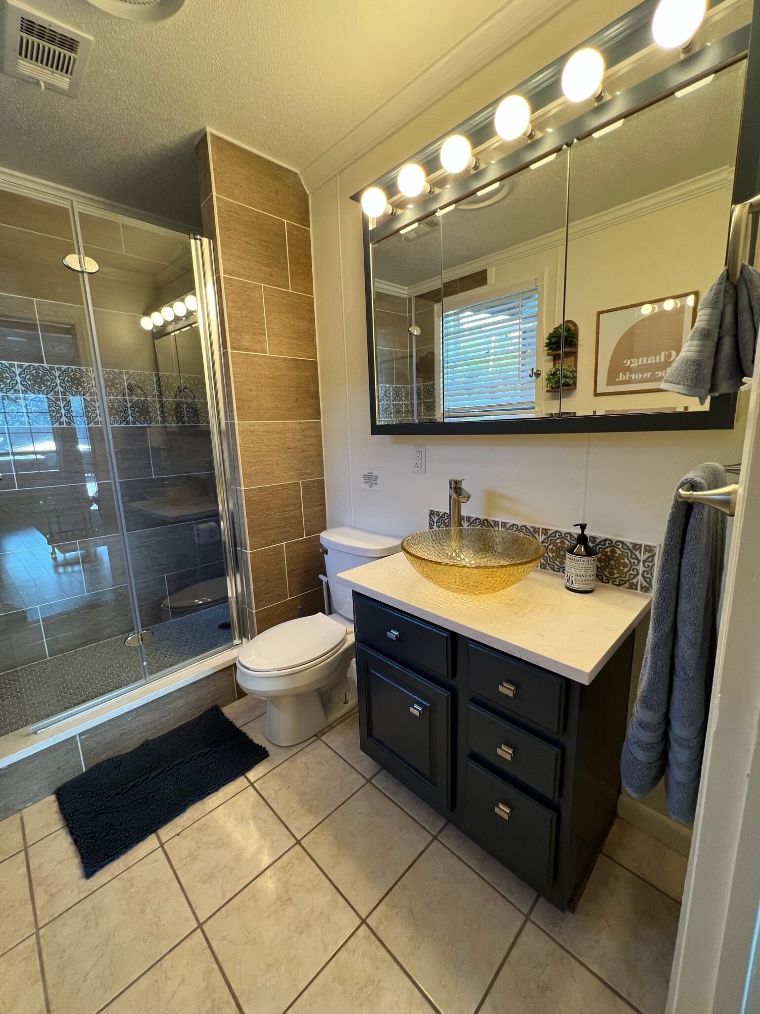 A modern bathroom with a glass shower enclosure, a vanity with a large mirror, and a toilet.