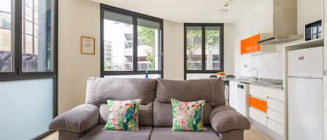 A modern living room with a sofa, a coffee table, and a view of the city through large windows.