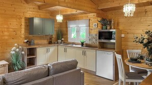 A cozy log cabin interior with a kitchen, dining area, and a sofa. - 1 bedroom accommodation in Rudyard, near Leek (Rudyard, near Leek)
