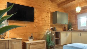 A cozy cabin interior with wooden walls, a flat-screen TV, a wooden cabinet, a blue sofa, and a small table with a decorative bowl. - 1 bedroom accommodation in Rudyard, near Leek (Rudyard, near Leek)
