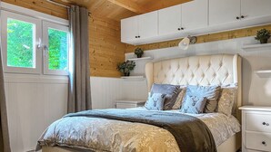 A bedroom with a large bed, wooden ceiling, white walls, and a window with curtains. - 1 bedroom accommodation in Rudyard, near Leek (Rudyard, near Leek)