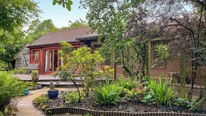 A house with a red roof and a garden with various plants and a pathway. - 1 bedroom accommodation in Rudyard, near Leek (Rudyard, near Leek)