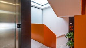 A modern elevator with a metallic finish, adjacent to a staircase with orange accents and a glass ceiling. - VIVENTE 3A BY CANARIAS GETAWAY (Las Palmas de Gran Canaria)