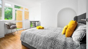 Une chambre à coucher moderne avec un grand lit, une chaise et une petite table.