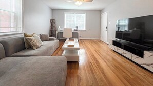 Ein modernes Wohnzimmer mit Sofa, Couchtisch, Fernseher und Deckenventilator.