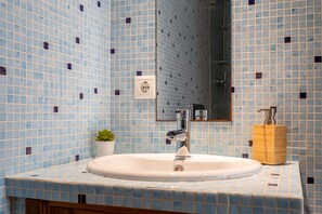 A bathroom with a sink, mirror, and a small potted plant. - Sesimbra Beach Apartment by GT House (Sesimbra)