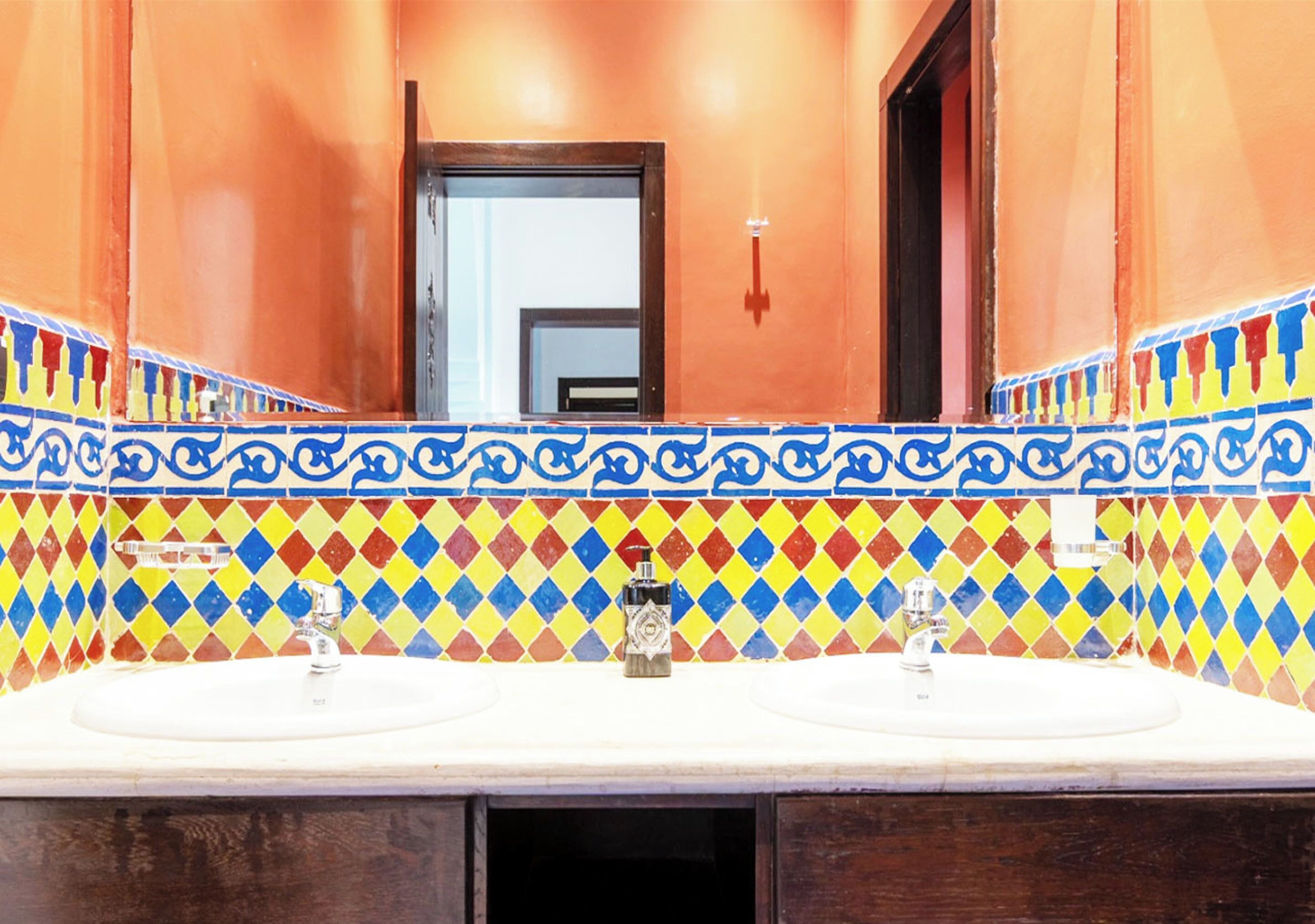 A bathroom with two sinks, a mirror, and a colorful tile backsplash.