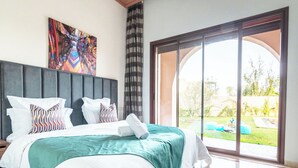 A large bed with white bedding and a teal throw, a grey headboard, and a colorful abstract painting above it. - Domaine Mandar Atlas (Marrakech)