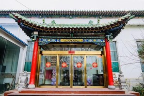 A traditional Chinese building entrance with a tiled roof and a red pillar.