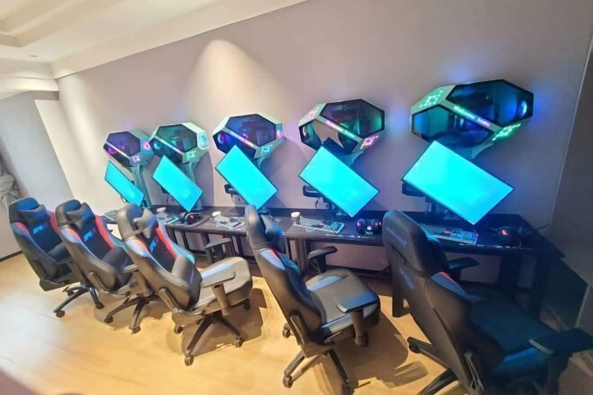 A gaming room with multiple gaming stations, each with a monitor and keyboard, and several gaming chairs.