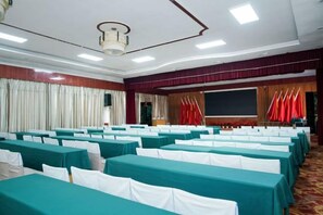 A conference room with rows of tables, a projector screen, and flags. - Xiang Qiu Hotel (Xiangyuan)