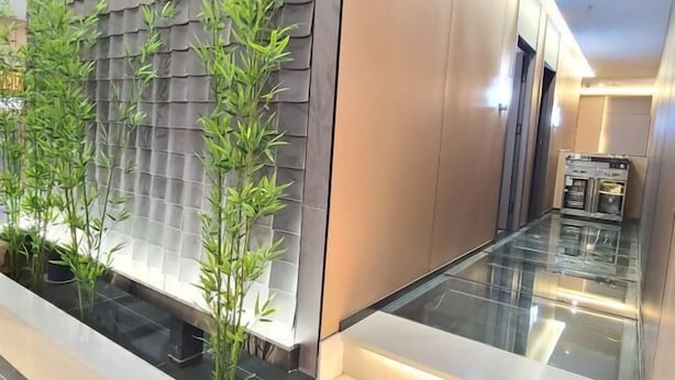 Un moderno vestíbulo de hotel con una pared de bambú, una mesa de centro de vidrio y un expendedor.