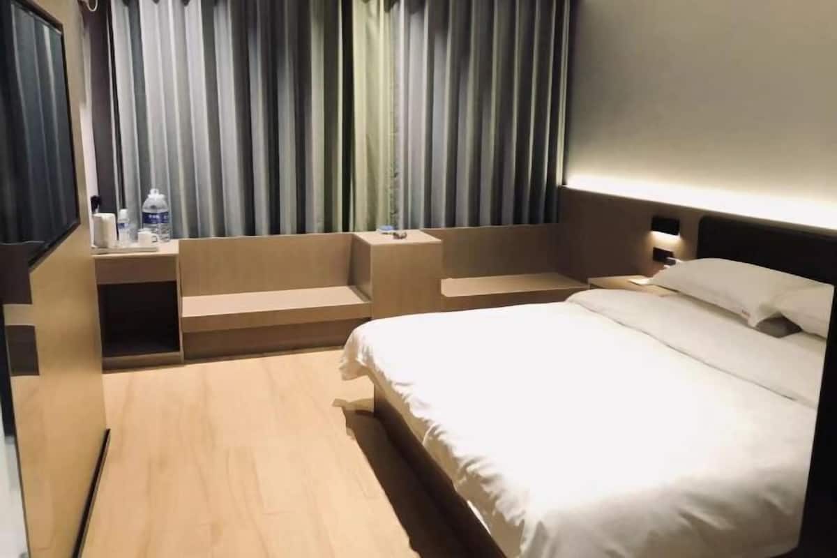 A hotel room with a bed, bedside tables, a mirror, and a curtain.