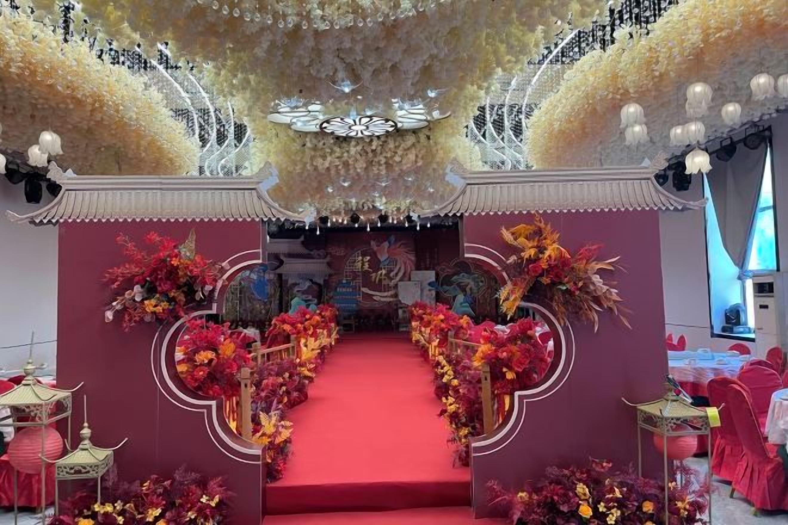 A stage with a red carpet, floral decorations, and traditional Asian architectural elements.