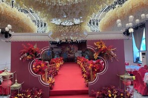 A stage with a red carpet, floral decorations, and traditional Asian architectural elements. - Xiang Qiu Hotel (Xiangyuan)