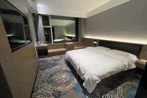 A modern hotel room with a large bed, a built-in desk, and a large mirror. - Xiang Qiu Hotel (Xiangyuan)