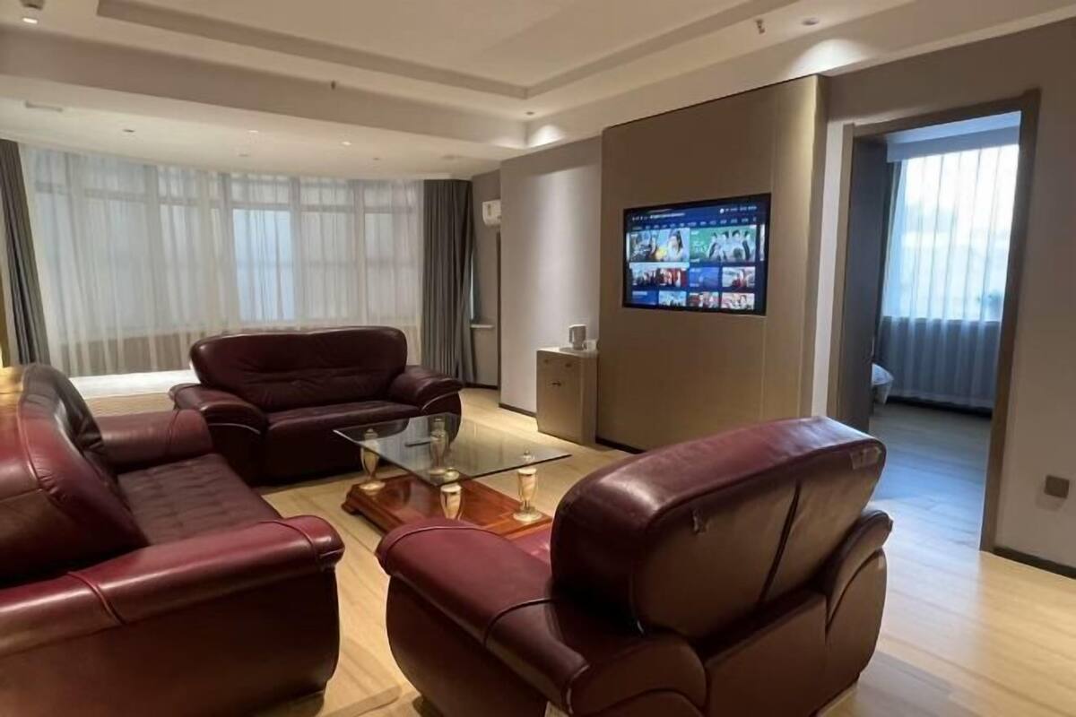 A modern living room with leather sofas, a glass coffee table, and a flat-screen TV mounted on the wall.