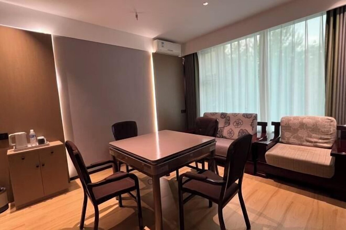 A modern hotel room with a dining table, chairs, a sofa, and a cabinet.