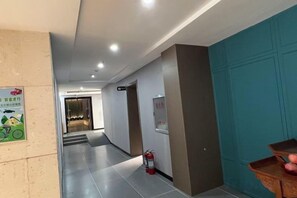 A hotel corridor with a fire extinguisher, a sign on the wall, and a door. - Xiang Qiu Hotel (Xiangyuan)