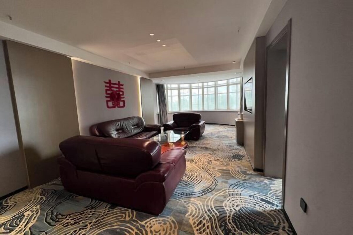 A modern hotel room with a leather sofa, a small coffee table, and a patterned carpet.