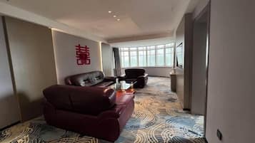 Una habitación de hotel moderna con un sofá de cuero, una mesita de centro pequeña y una alfombra estampada.