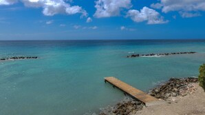 Eine hölzerne Pier erstreckt sich in türkisfarbenes Wasser, umgeben von Felsen.