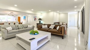 Ein modernes Wohnzimmer mit zwei Sofas, einem Couchtisch und einer Essecke im Hintergrund.