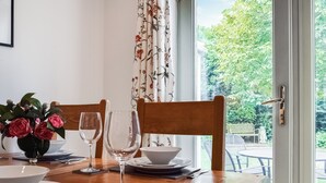 A dining table set with plates, bowls, and wine glasses, with a vase of flowers on the left. - 2 bedroom accommodation in Eynsham (Eynsham)
