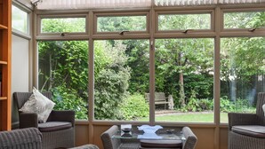 A sunroom with large windows, wicker furniture, and a glass coffee table. - 2 bedroom accommodation in Eynsham (Eynsham)