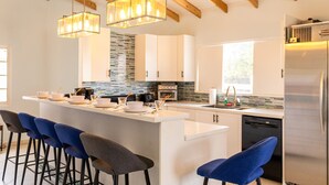 Una cocina moderna con una isla central, taburetes de bar e iluminación colgante.