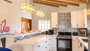 Una cocina moderna con una isla grande, armarios blancos, un salpicadero azulejado y techo de madera.