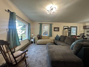 A living room with a sofa, a rocking chair, a lamp, and a ceiling fan.