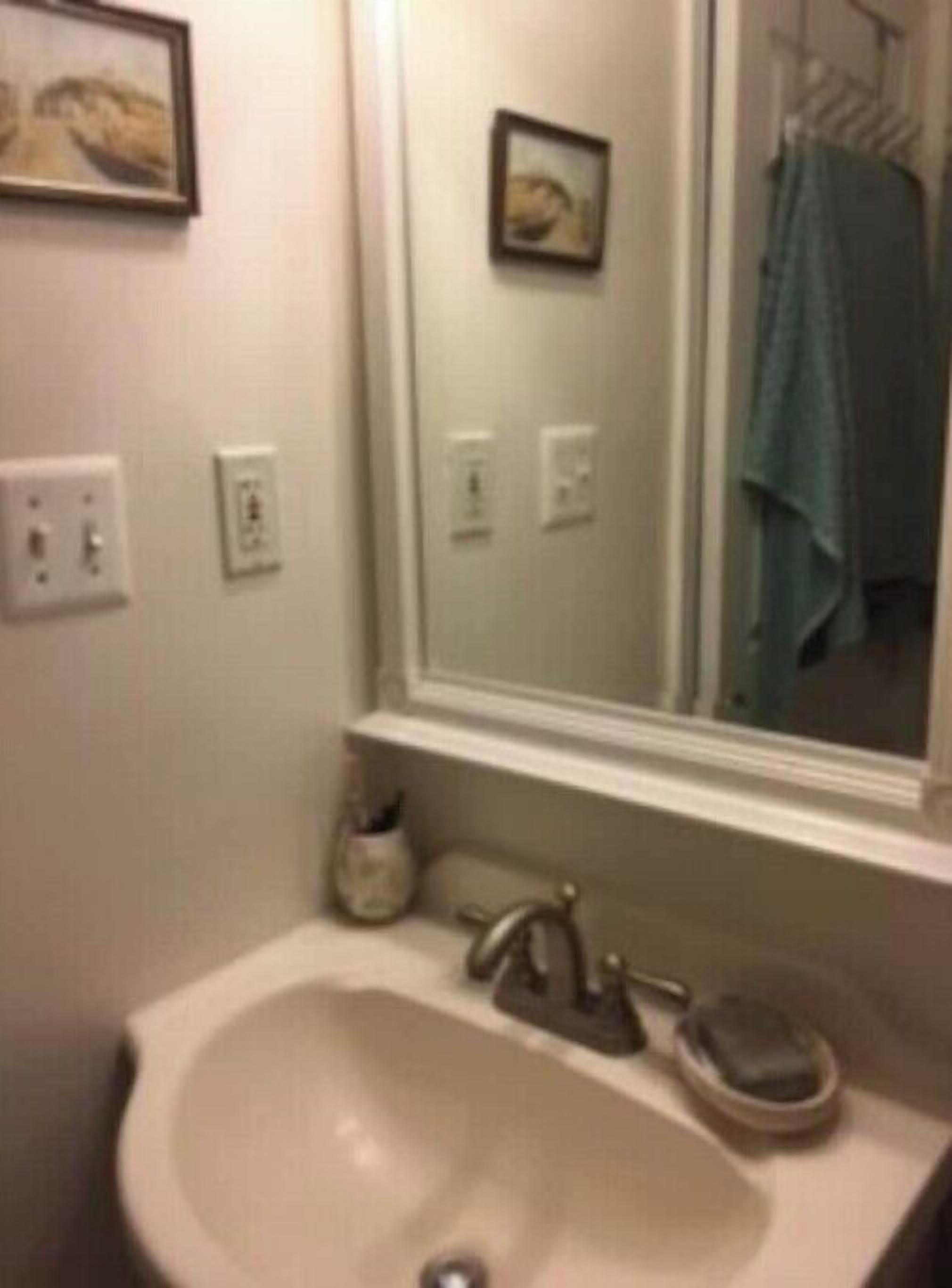 A bathroom with a sink, a mirror, and a towel rack.