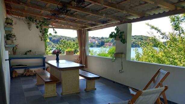 Ein Balkon mit Tisch, Bänken und Blick auf einen See und Hügel.