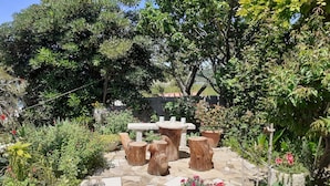 Eine Gartenpatio mit Steinböden, rustikalen Holzstühlen und einem Steintisch.