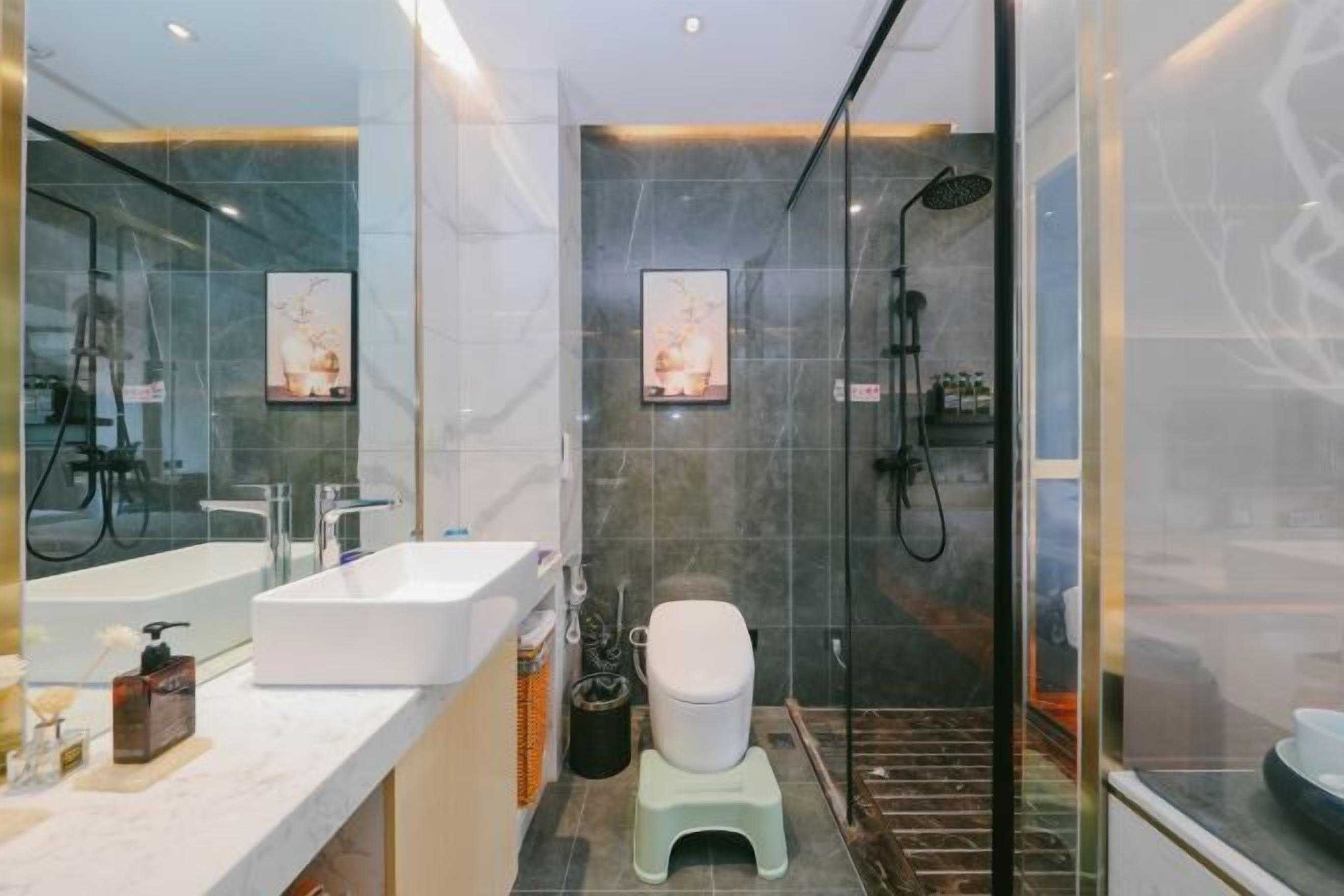 A modern bathroom with a large mirror, a white sink, a toilet, and a shower area.