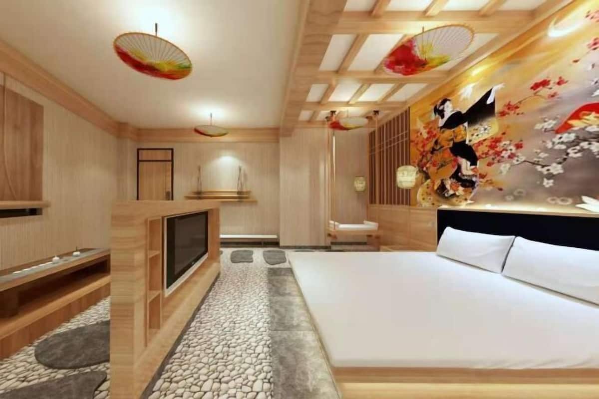 Un dormitorio con cama, televisor, paneles de madera, piso con diseño de piedra y una pared con una pintura tradicional.