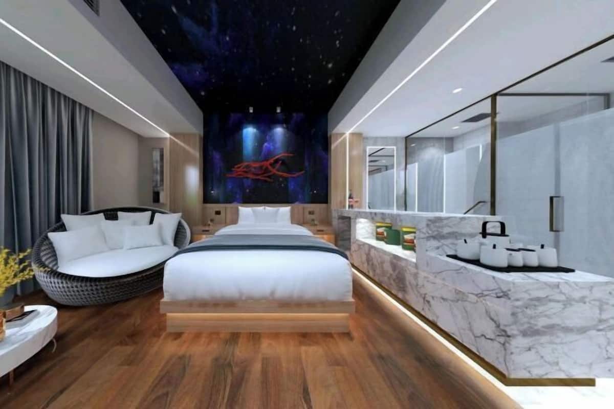 Un dormitorio moderno con cama, zona de estar, tocador con espejo y una pared con un mural celestial.