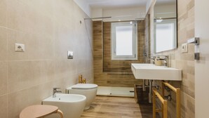 A modern bathroom with a shower, toilet, and sink, featuring wooden accents and a large mirror. - Casa Eleonora con Balcone by Wonderful Italy (Catania)