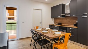 A modern kitchen with dark cabinets, a wooden countertop, and a dining area with a table set for four. - Casa Eleonora con Balcone by Wonderful Italy (Catania)
