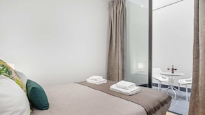 A hotel room with a bed, a small table with chairs, and a view of the outside. - Funchal Tropical - Filodendro by Homie (Funchal)